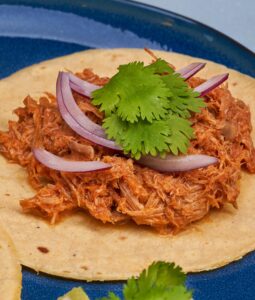 Photo de Cochinita Pibil, plat de la péninsule du Yucatán, à base de porc mariné dans du roucou, enveloppé dans une feuille de bananier et cuit dans un four enterré, connu sous le nom de píib.
