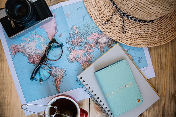 Chapeau, lunettes et passeport sur une carte, symbolisant le voyage.