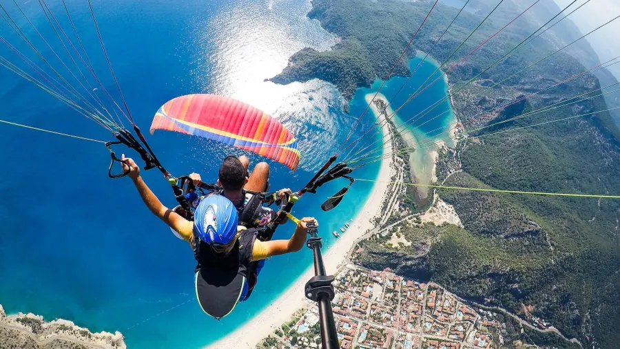 Une personne fait du parapente au-dessus de l'océan sous un ciel bleu clair