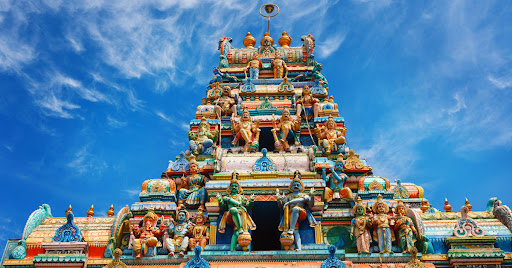 Un temple hindou aux couleurs vives, surmonté de statues, symbolisant la tradition et l'art religieux.